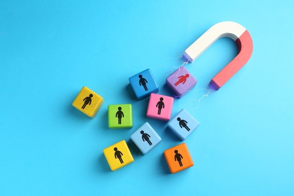 Magnet attracting colorful cubes with human figures on a light blue background